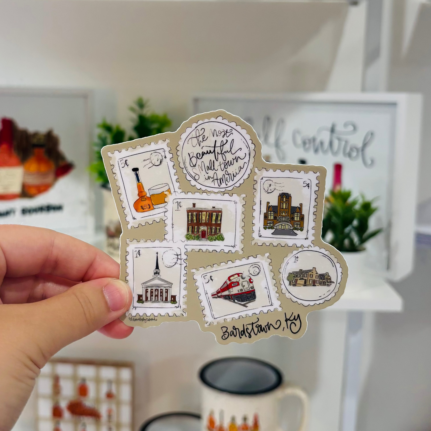 A hand holding a sticker with stamps representing Bardstown Kentucky