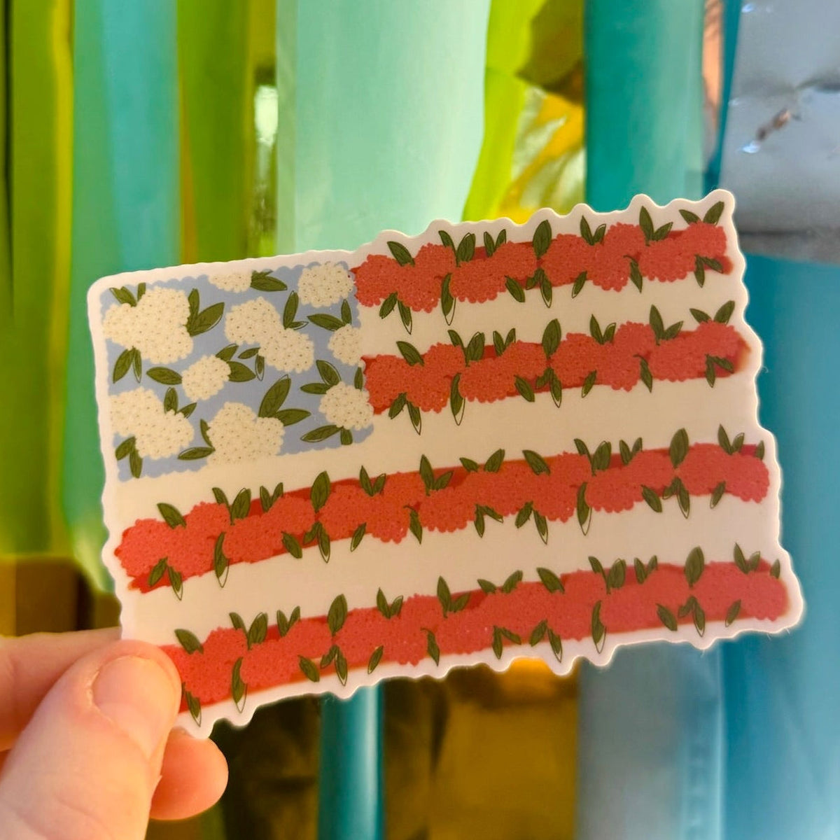 Doodles by Rebekah floral American flag vinyl sticker. This whimsical hand-painted patriotic decal features a botanical take on the U.S. flag, making it a perfect gift for Independence Day or year-round decor for water bottles, laptops, and planners.