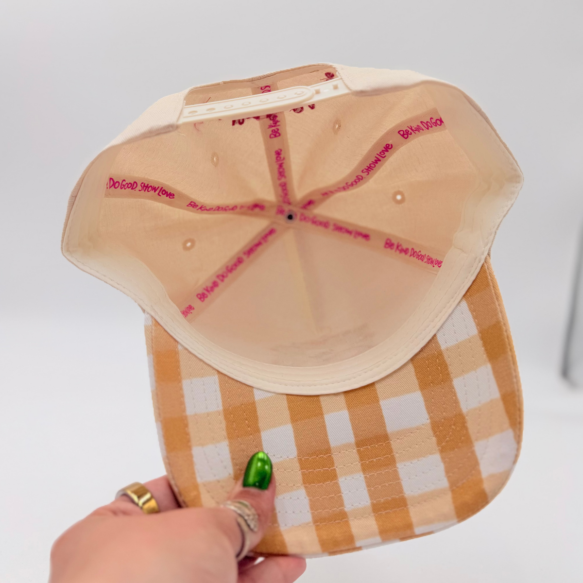 Hand holding a checkered cap with a paper template on a white background