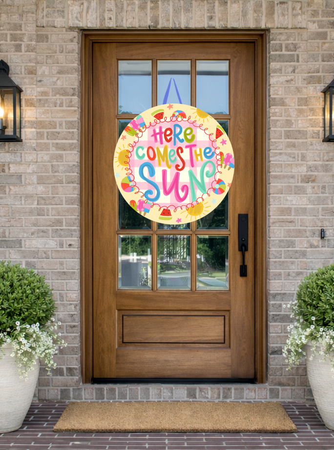 Doodles by Rebekah "Here Comes the Sun" summer door decor featuring a colorful, hand-drawn seasonal design on a rustic glass-paned front door.