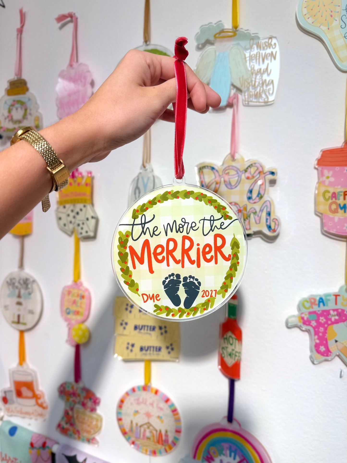 The more the merrier ornament featuring baby feet held by a hand