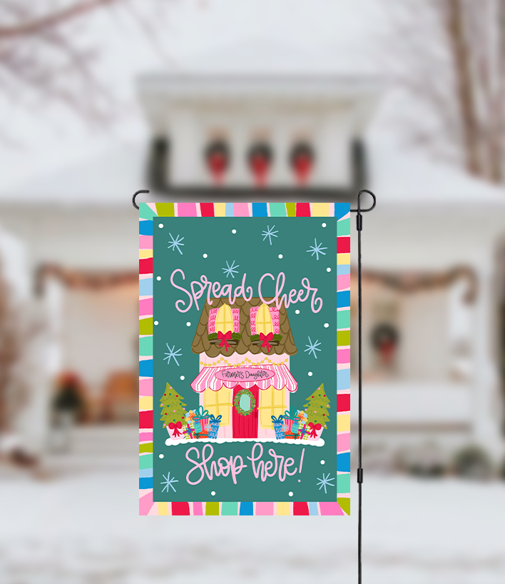 Decorative garden flag with a colorful border and festive text in front of a blurred snowy background.