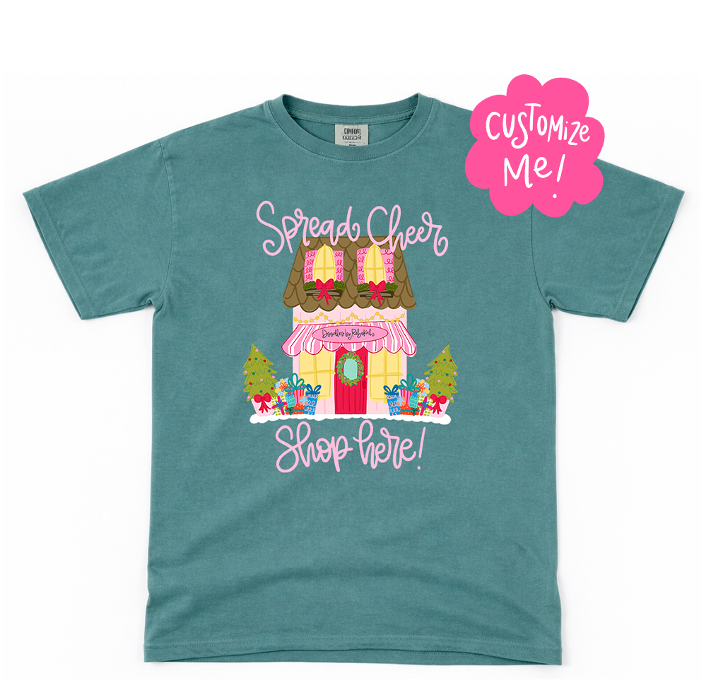 Teal t-shirt with a festive store graphic and 'Customize Me!' text on a white background