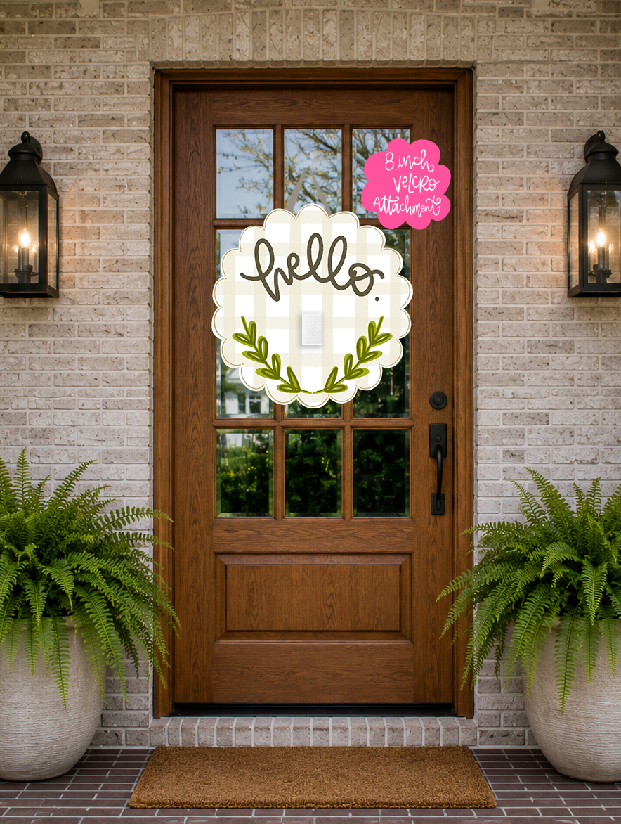 Decorative 'hello' sign on a wooden door with potted ferns on either side.