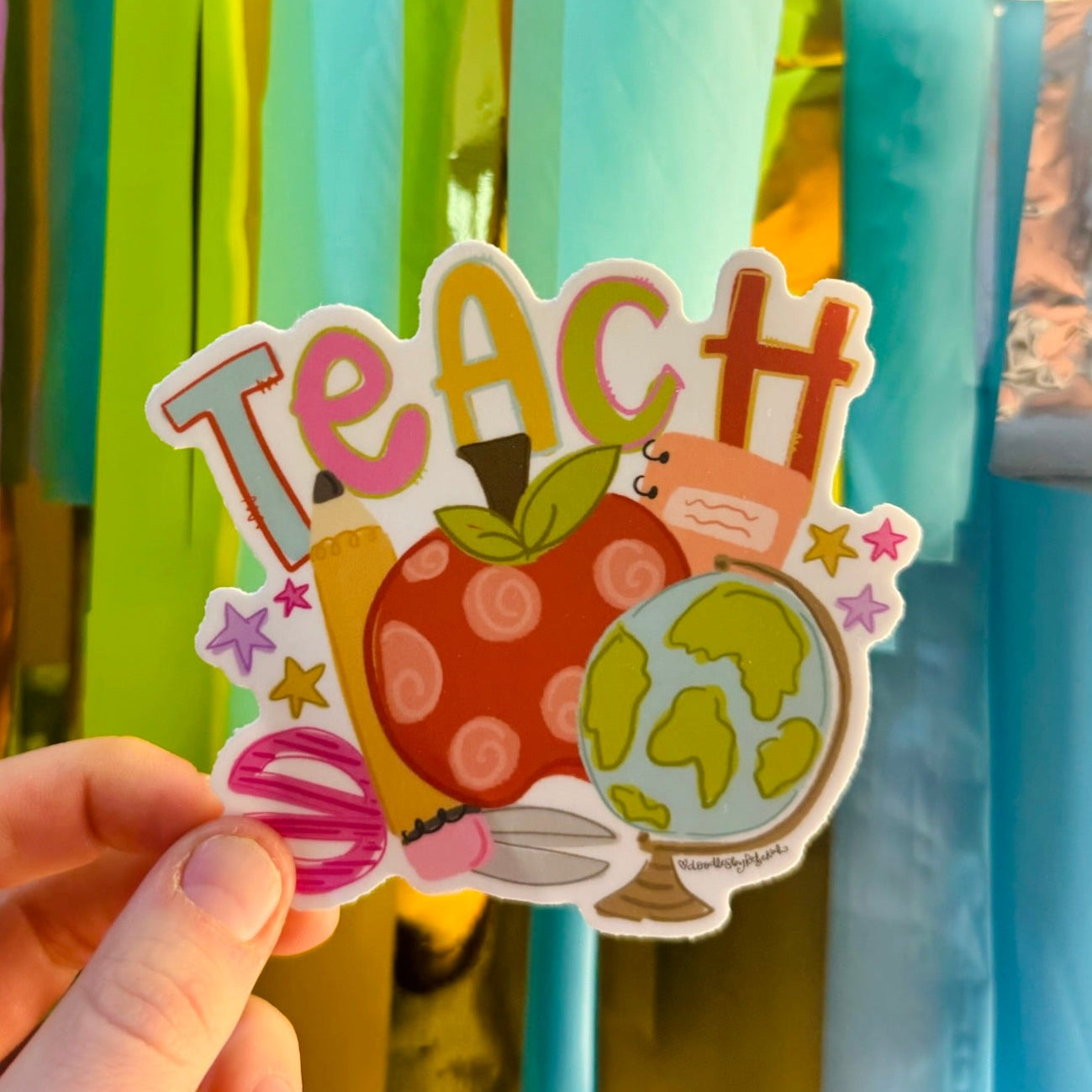 Doodles by Rebekah "TEACH" teacher sticker. This colorful hand-painted die-cut vinyl decal features whimsical school icons like an apple, globe, and pencil, making it the perfect teacher appreciation gift for water bottles, laptops, or planners.