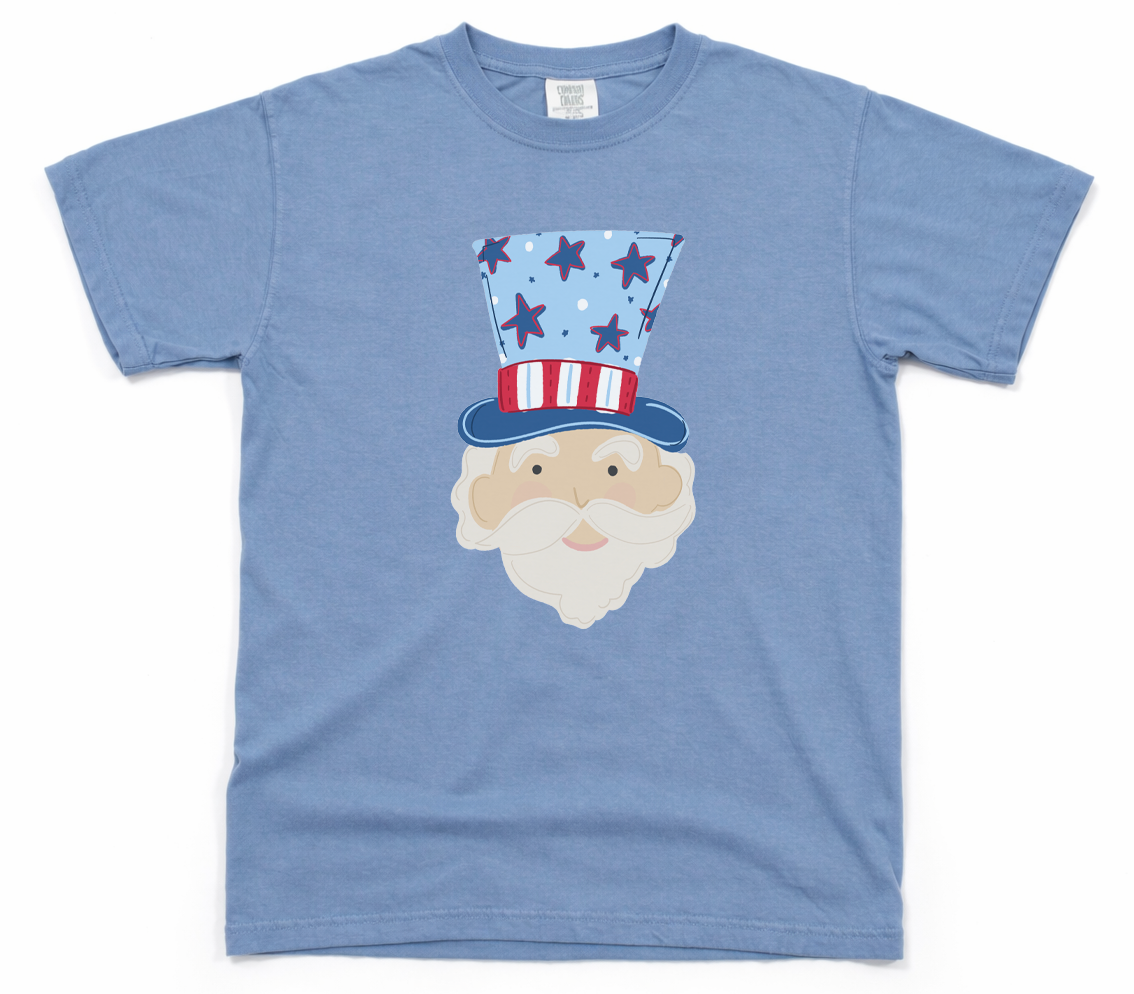 Blue t-shirt with a graphic of a face wearing an American flag hat on a white background