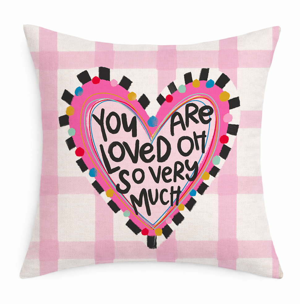 A pink and white gingham pillow with a decorative heart that says "You Are Loved Oh So Very Much Pillow" on a white background