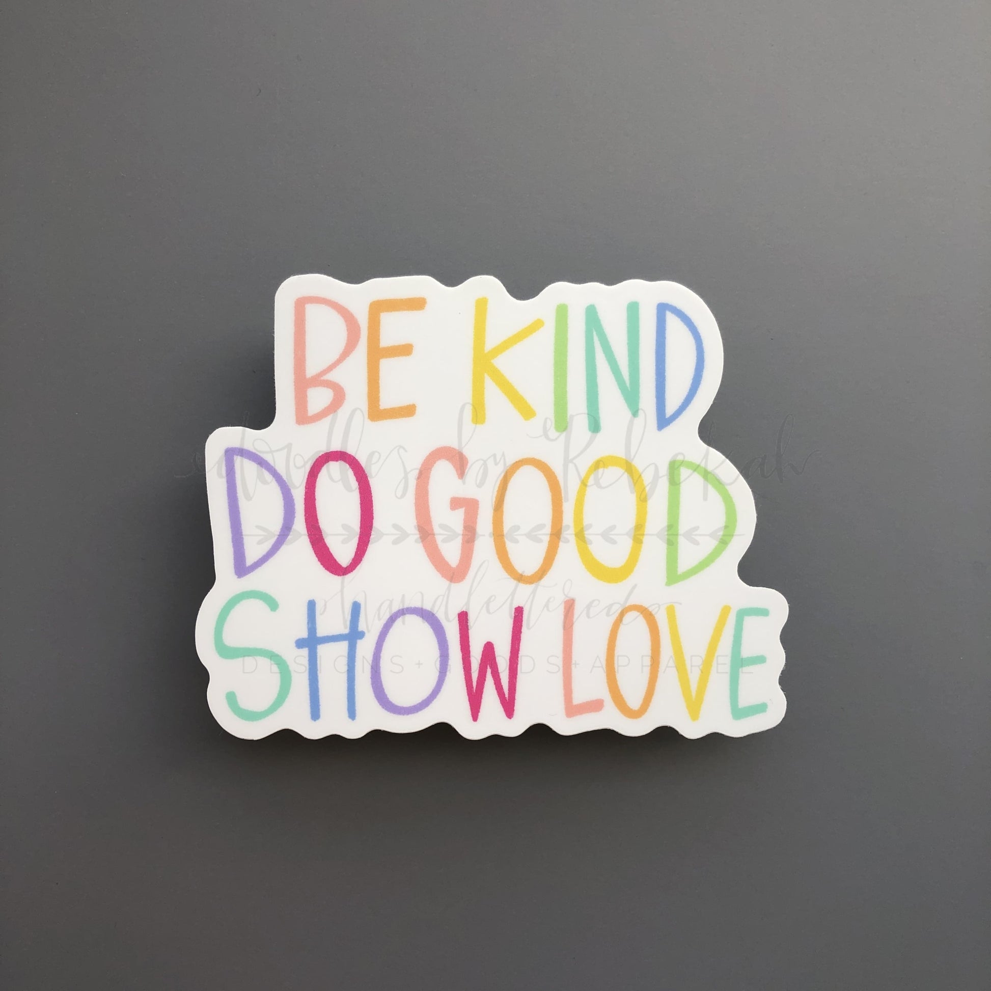A colorful sticker with the phrase 'BE KIND DO GOOD SHOW LOVE' written in multicolored letters.