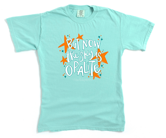Light blue t-shirt with colorful text and star graphics on a white background