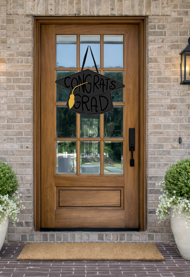 Doodles by Rebekah graduation door decor featuring a whimsical black grad cap illustration with a gold tassel on a rustic wooden front door.