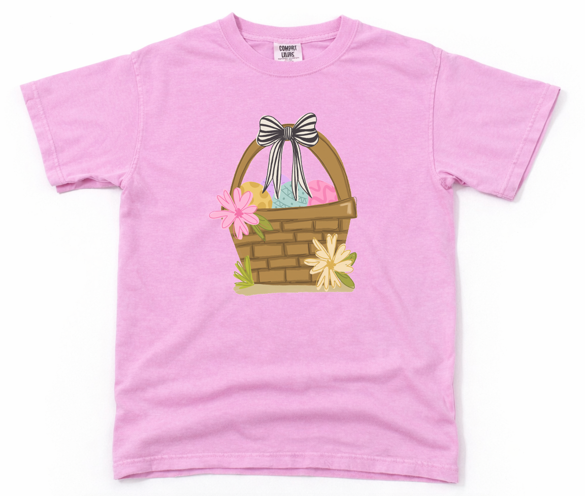 Pink t-shirt with a graphic of an Easter basket on a white background