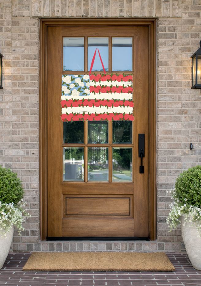 Doodles by Rebekah floral American flag door decor featuring a whimsical hand-drawn flower pattern on a rustic front porch.