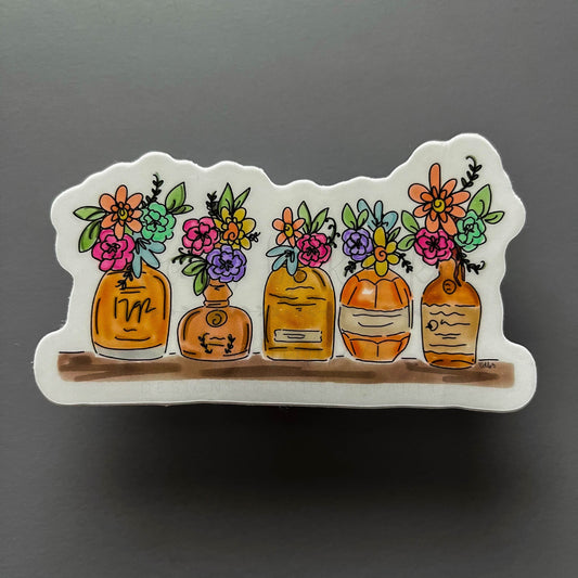 Sticker with bourbon bottles on a shelf holding wild flowers
