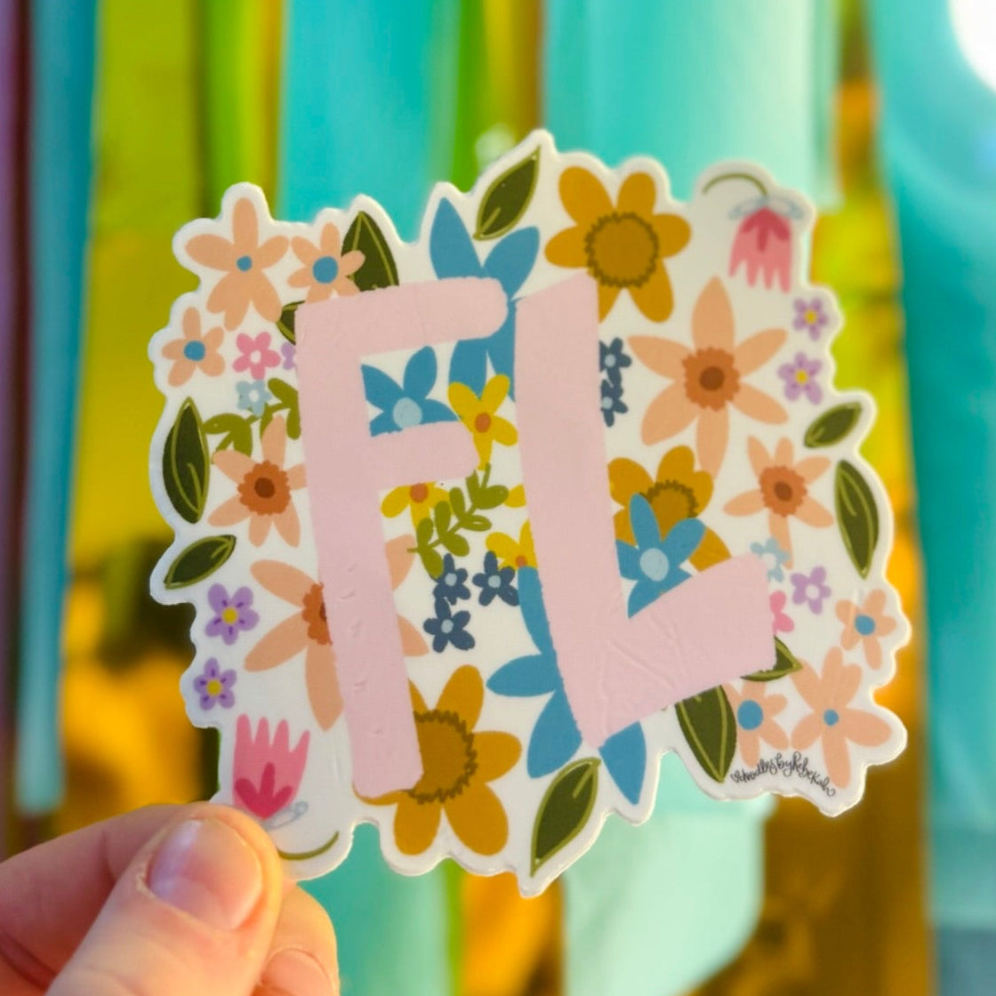 Doodles by Rebekah floral Florida (FL) state abbreviation sticker. This whimsical botanical vinyl decal features a colorful wildflower pattern, making it a perfect sunshine-state gift for decorating water bottles, laptops, and travel journals.