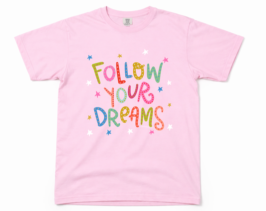 Pink t-shirt with 'Follow Your Dreams' text on a white background