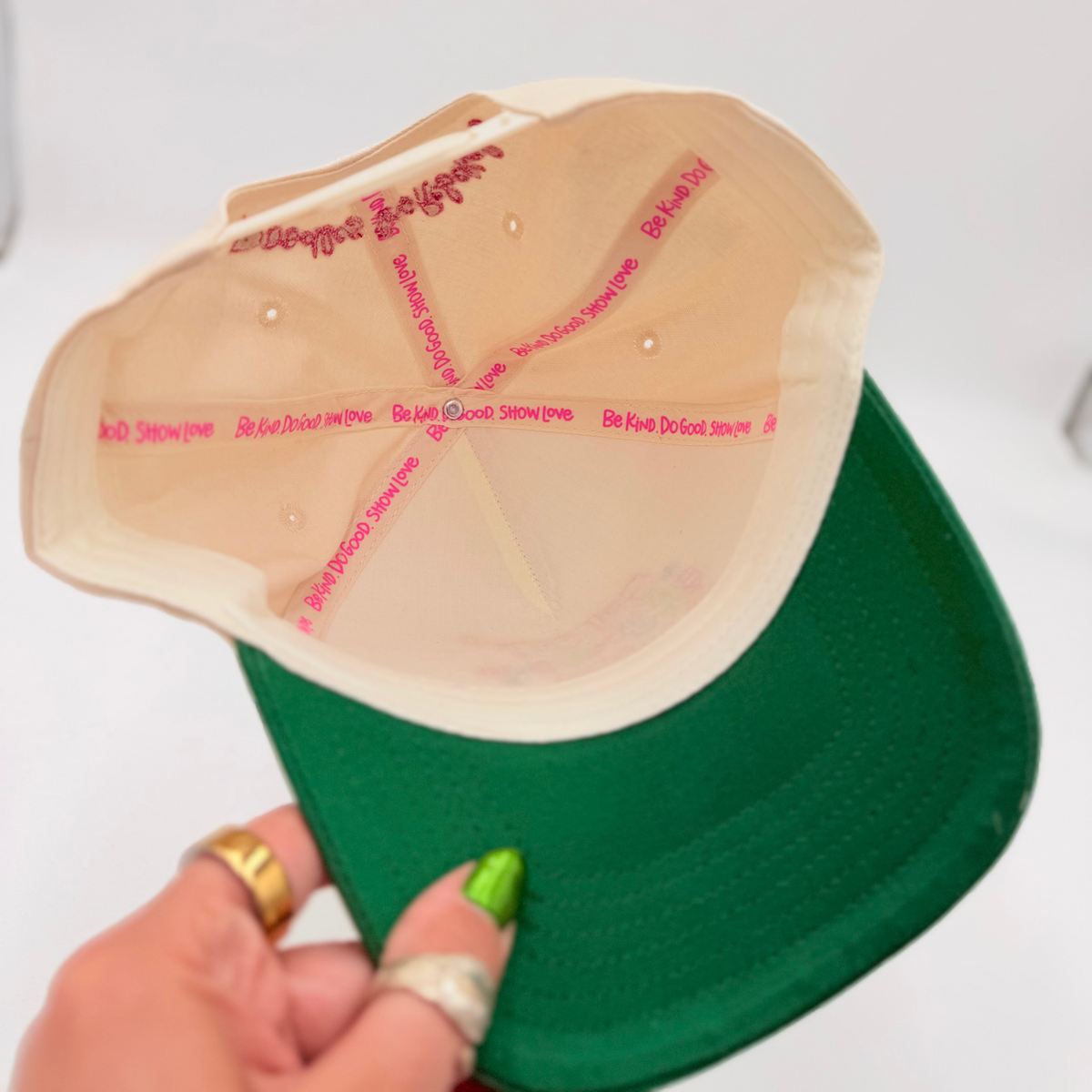 Green cap with a beige interior held by a hand.