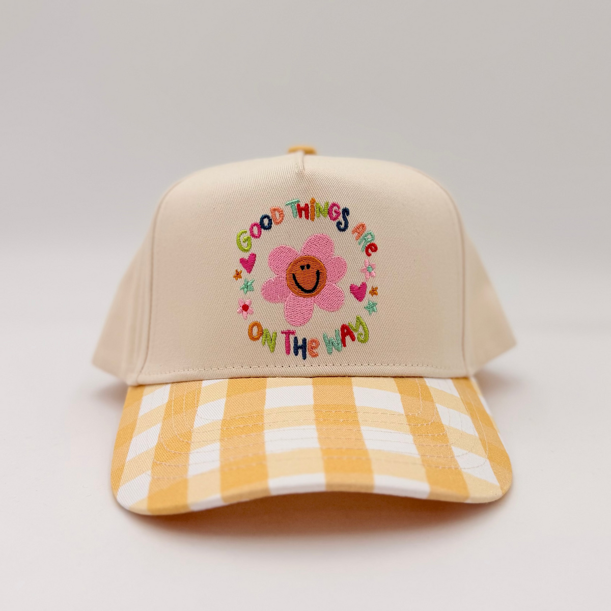 Beige cap with floral design and text on a light gray background