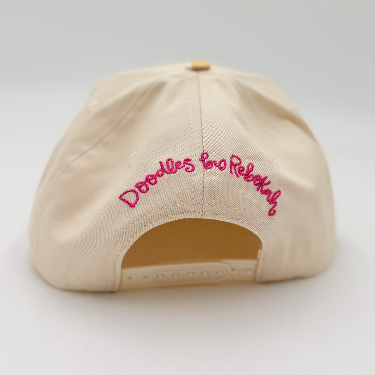 Beige cap with pink text on a light gray background