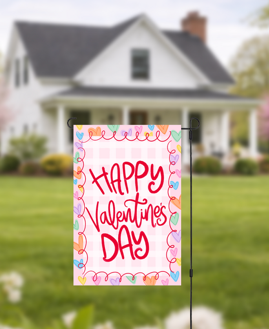 Doodles by Rebekah "Happy Valentine's Day" garden flag featuring whimsical red hand-painted typography and a pink checkered pattern. This cheerful outdoor holiday decor is perfect for Valentine's Day celebrations or adding a touch of love to front yard landscaping.