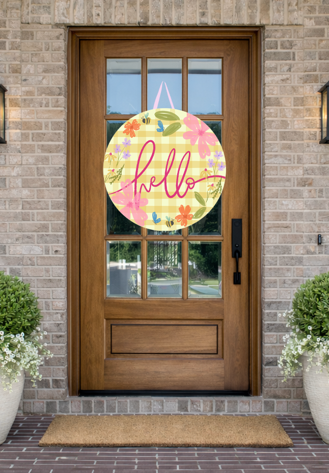 Doodles by Rebekah "hello" spring door decor featuring a whimsical hand-painted design with a yellow gingham background and garden illustrations on a rustic front porch.