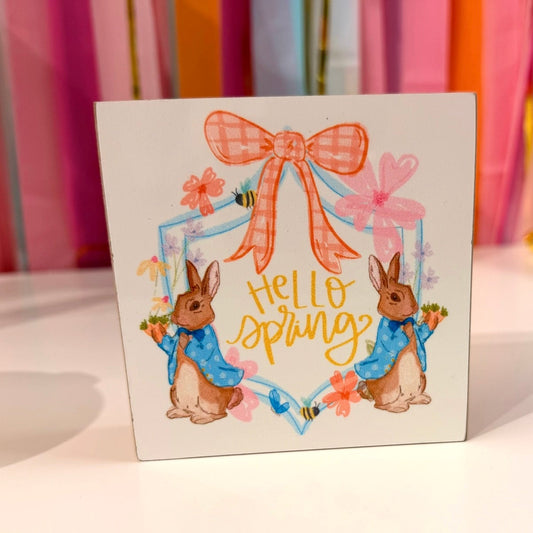 Doodles by Rebekah patriotic Uncle Sam wooden block home decor featuring a whimsical hand-painted design on a pink checkered pattern. This Americana-themed tabletop or shelf accent is shown against a bright party streamer background.