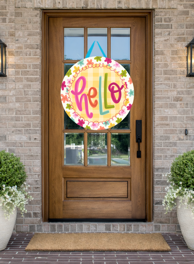 Doodles by Rebekah "hello" floral door decor featuring a whimsical hand-painted design with a yellow gingham background and spring blossoms on a rustic front porch.