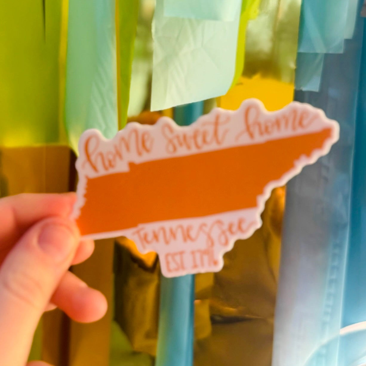 Doodles by Rebekah "Home Sweet Home Tennessee" state pride sticker. This whimsical orange vinyl decal is a perfect gift for Tennessee residents or as a souvenir, ideal for decorating water bottles, laptops, and planners.