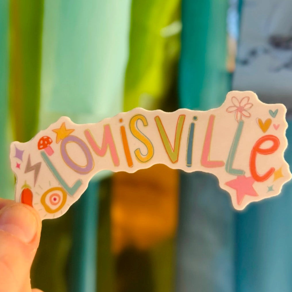 Doodles by Rebekah Louisville, Kentucky rainbow typography sticker. This whimsical hand-painted vinyl decal features colorful pastel lettering and cute boho icons, making it a perfect souvenir or gift for Louisville residents to decorate water bottles, laptops, and journals.
