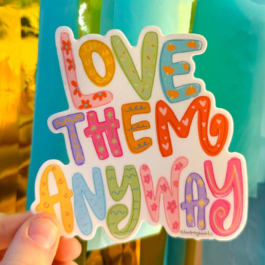 Doodles by Rebekah "LOVE THEM ANYWAY" whimsical patterned vinyl sticker. This colorful, hand-painted lettering decal features a message of kindness and patience, making it a perfect gift for teachers, parents, and counselors to decorate water bottles, laptops, and planners.
