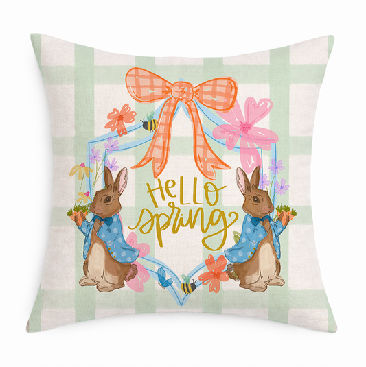 Decorative pillow with 'Hello Spring' text and bunny illustrations on a plaid background.