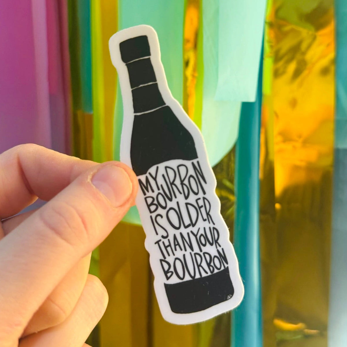 Doodles by Rebekah "My Bourbon is Older Than Your Bourbon" vinyl sticker. This funny hand-painted whiskey-themed decal is a perfect gift for bourbon enthusiasts and Kentucky locals to decorate water bottles, laptops, and home bars.