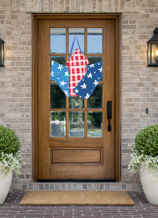 Doodles by Rebekah patriotic fireworks door decor featuring red, white, and blue rocket illustrations, displayed on a rustic wooden front door.