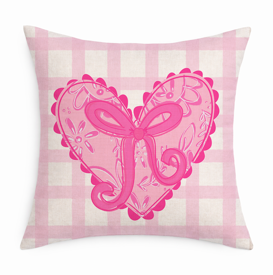 Decorative pillow with pink heart and bow design on a pink and white checkered background