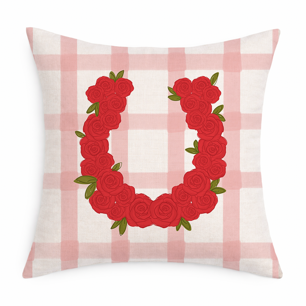 Decorative pillow with red rose wreath design on a pink and white checkered background