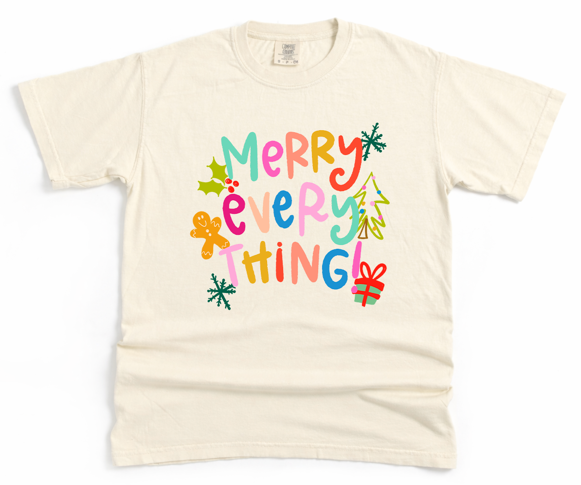 Beige t-shirt with colorful 'Merry Everything' text and Christmas graphics on a white background