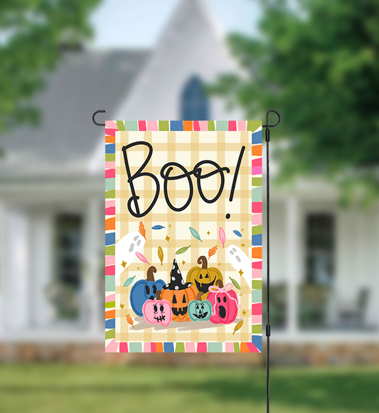 Decorative garden flag with 'Boo!' and pumpkins in front of a house.