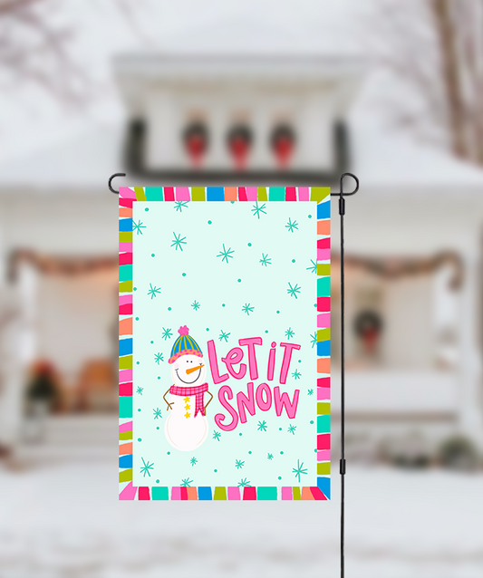 Decorative garden flag with 'Let It Snow' text and snowman graphic, set against a snowy background.