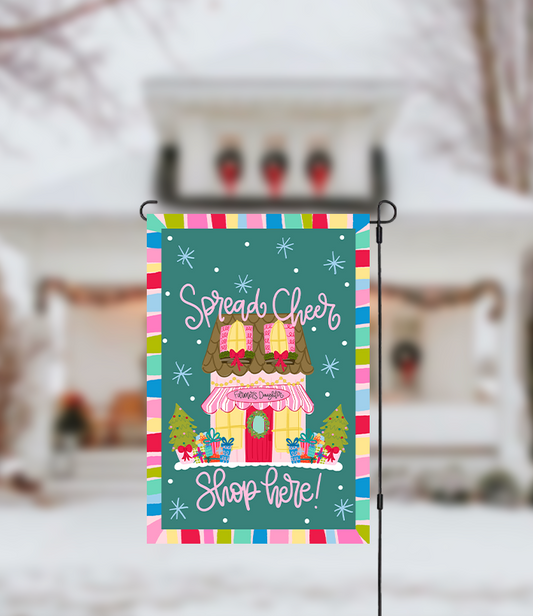 Decorative garden flag with a colorful border and festive text in front of a blurred snowy background.