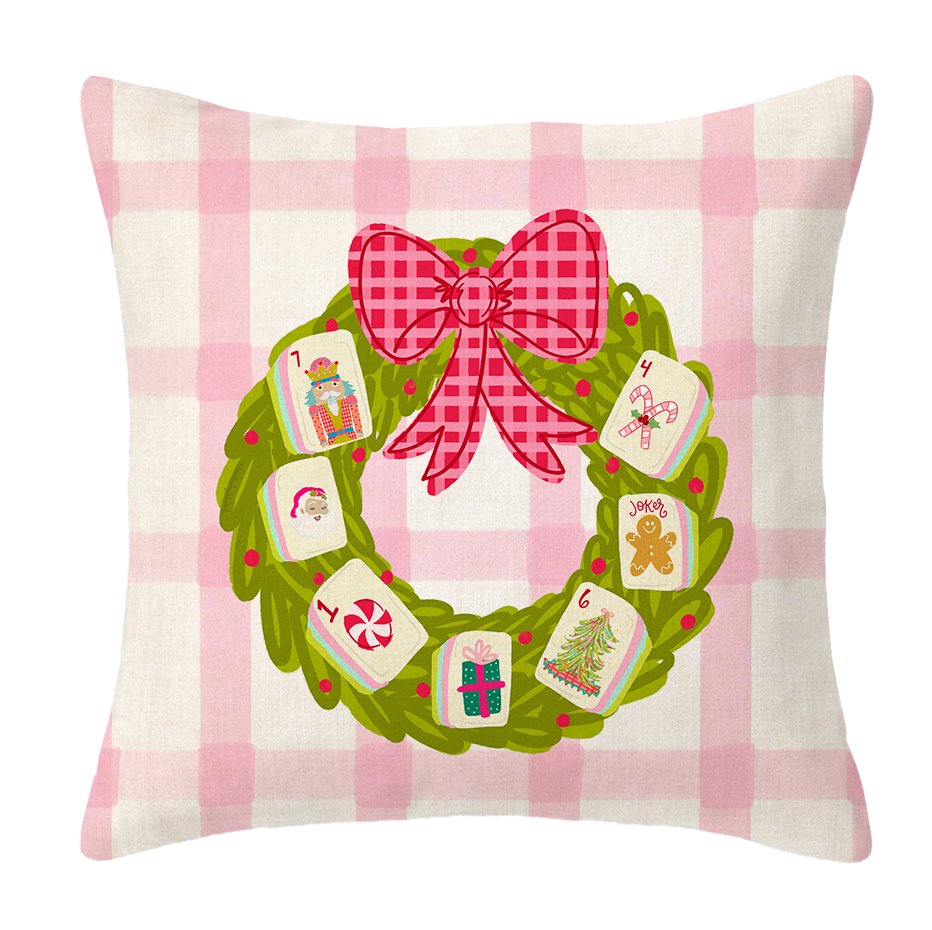 A pink & white plaid pillow with a wreath and Mahjong tiles on it