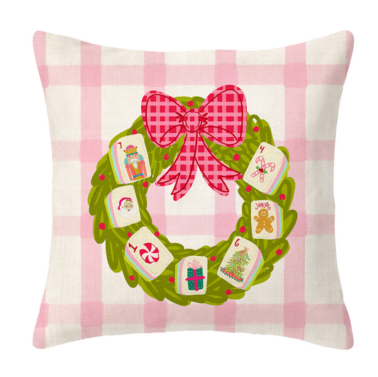 A pink & white plaid pillow with a wreath and Mahjong tiles on it