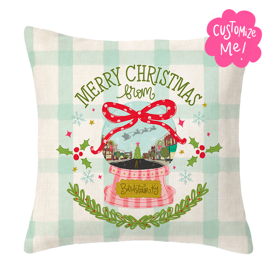 Decorative pillow with Christmas design featuring a snow globe and 'Merry Christmas' text on a checkered background.