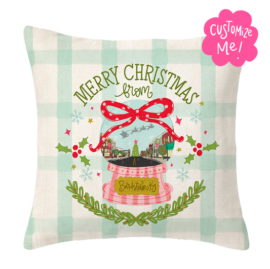 Decorative pillow with Christmas design featuring a snow globe and 'Merry Christmas' text on a checkered background.