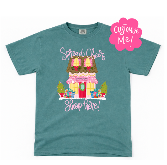Teal t-shirt with a festive store graphic and 'Customize Me!' text on a white background
