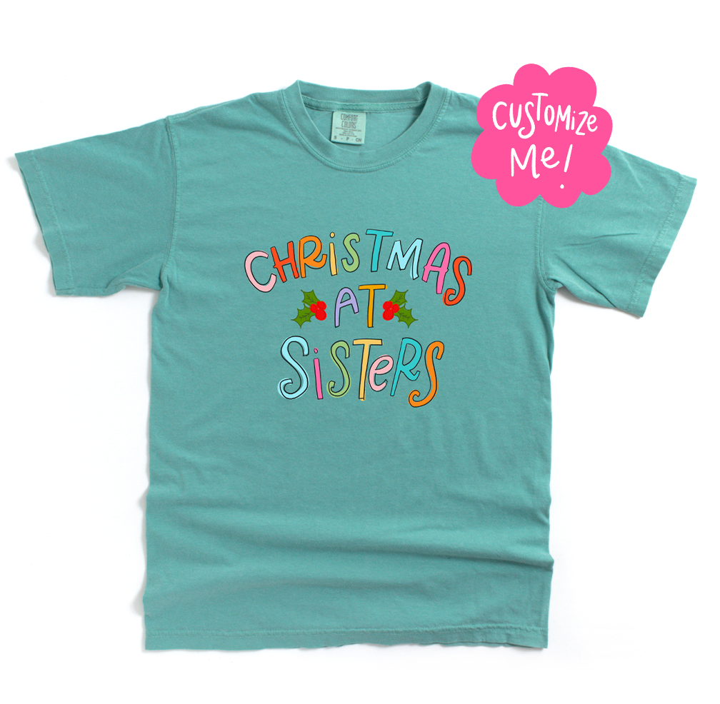 Teal t-shirt with 'Christmas at Sisters' text on a white background
