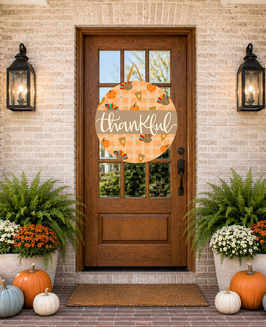 Front door with a 'thankful' sign, pumpkins, and potted plants on a brick wall.