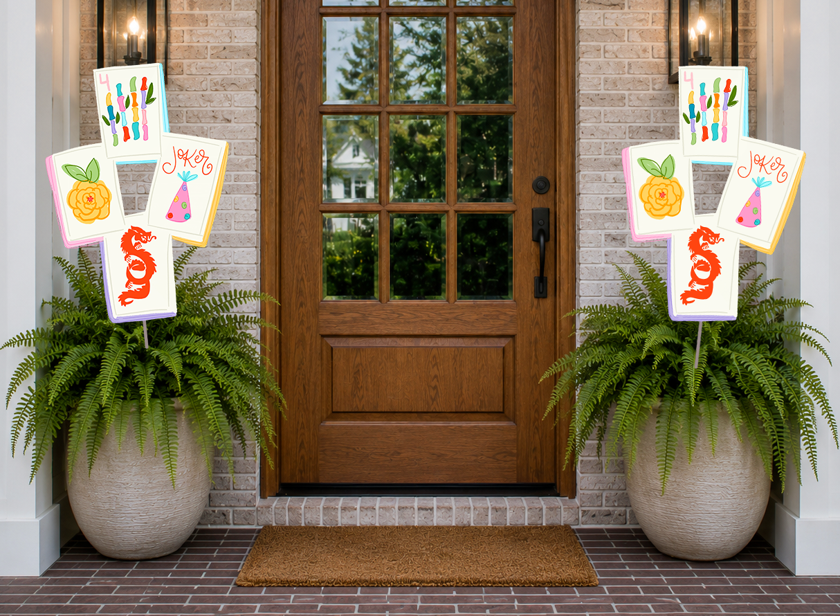 Decorative signs with colorful designs on a door with potted plants on either side.