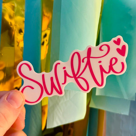 Doodles by Rebekah "Swiftie" pink script vinyl sticker. This whimsical hand-painted fan decal is a perfect gift for music lovers to decorate water bottles, laptops, and concert journals.