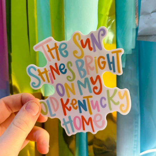 Doodles by Rebekah "My Old Kentucky Home" sticker. This colorful hand-painted vinyl decal features lyrics from the Kentucky state song in bright, whimsical typography, making it a perfect gift for Kentucky residents, graduates, or state pride fans to use on water bottles and laptops.