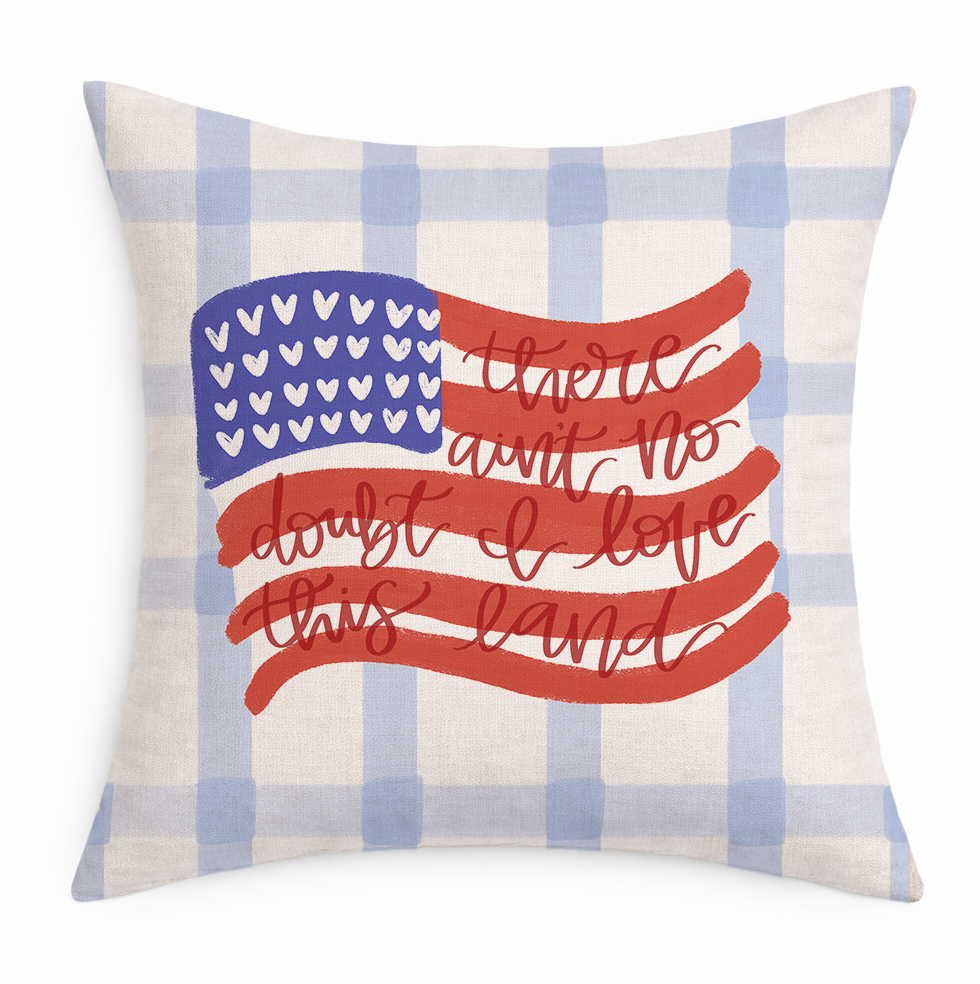 Decorative pillow with American flag design and text on a plaid background