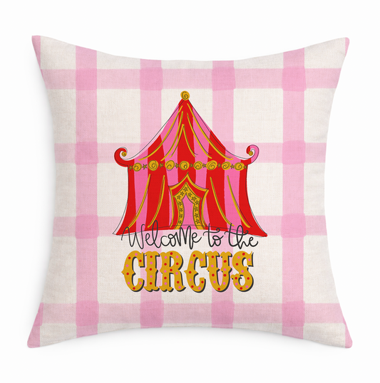 Decorative pillow with a circus tent design and 'Welcome to the Circus' text on a pink and white checkered background.